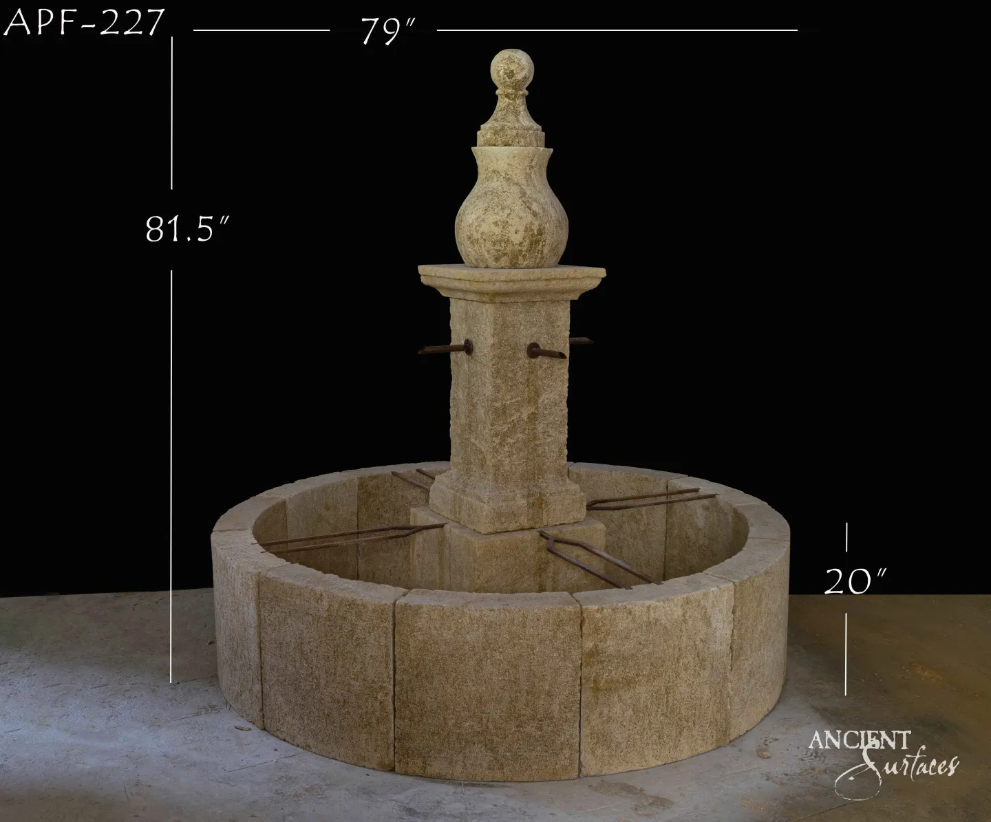 Round reclaimed antique limestone pool fountain from Ancient Surfaces built of rough faced honey toned blocks, with a square tapering pillar, two plain iron spouts and a carved vase and ball finial