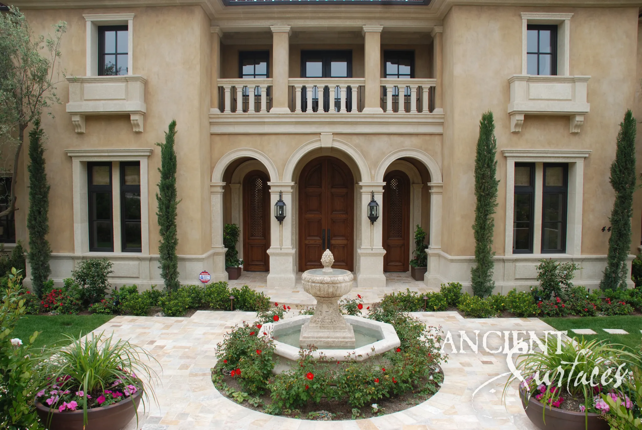 Reclaimed antique limestone pool fountain from Ancient Surfaces in an octagonal pool on a paved forecourt, a moulded pedestal carrying a gadrooned bowl and a carved pinecone finial