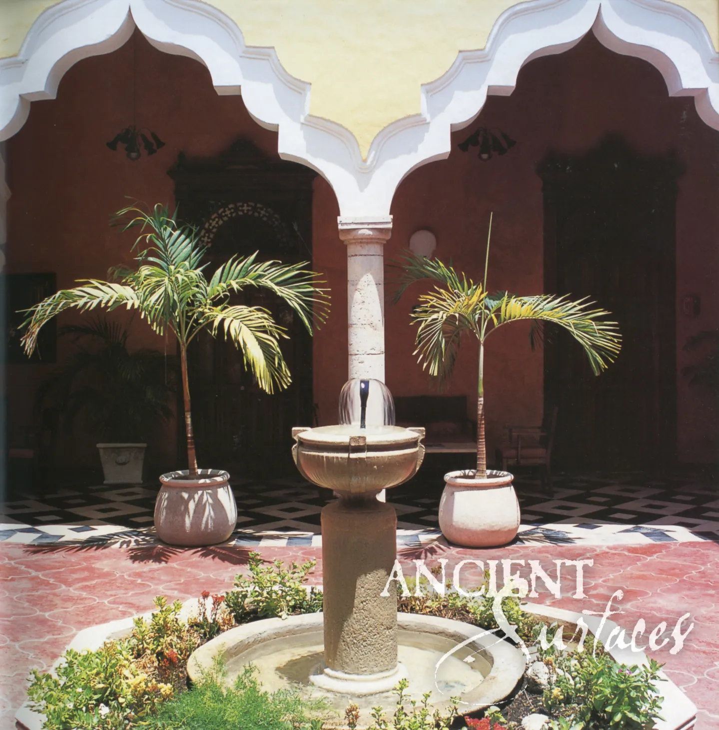 Slender reclaimed antique limestone courtyard fountain from Ancient Surfaces, a coarse textured cylindrical shaft carrying a shallow lobed bowl with a single jet, standing in a low circular basin